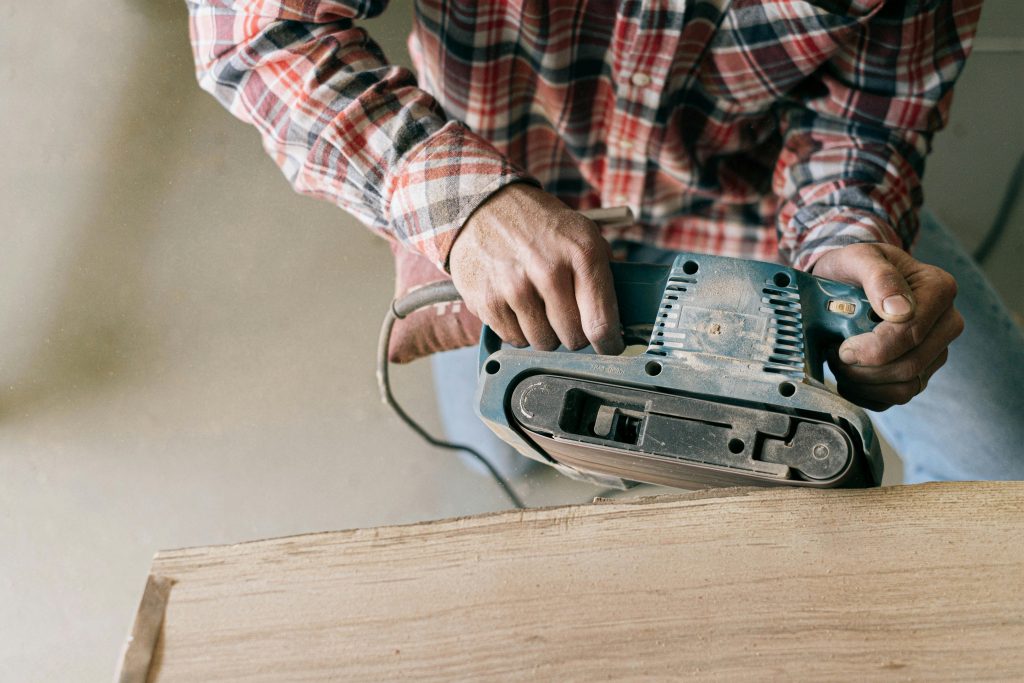 Close-up of a skilled craftsman sanding wood for custom furniture, representing bespoke interior design services near me